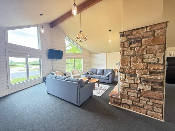 a dining hall with stainless steel appliances kitchen island granite countertop a table chairs and a refrigerator
