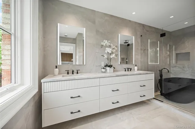 a bathroom with a tub sink double vanity and a mirror