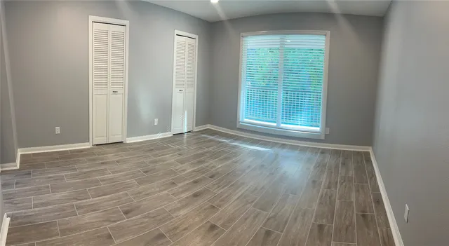 a view of an empty room with wooden floor and a window