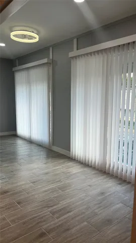 an empty room with wooden floor and natural light