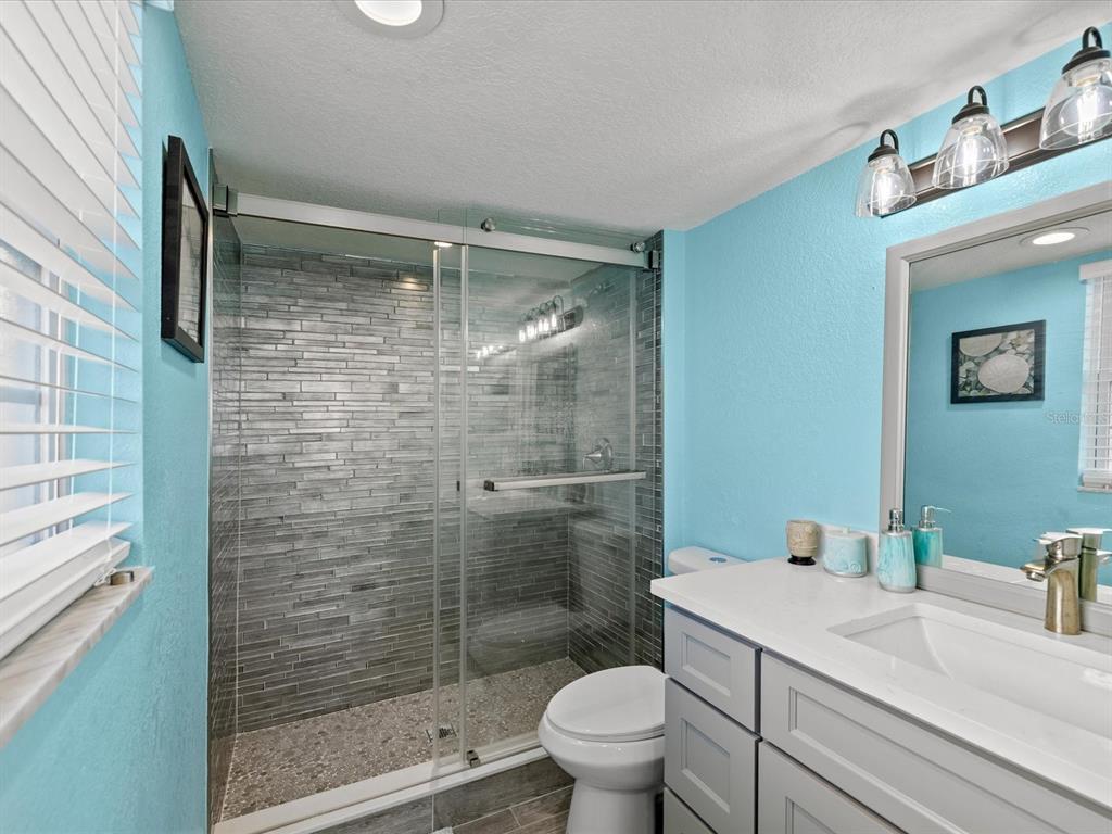 205 Dolphin Point, Unit 4 Clearwater Beach, FL 33767 - Photo 12 of 23 a bathroom with a granite countertop sink toilet and shower