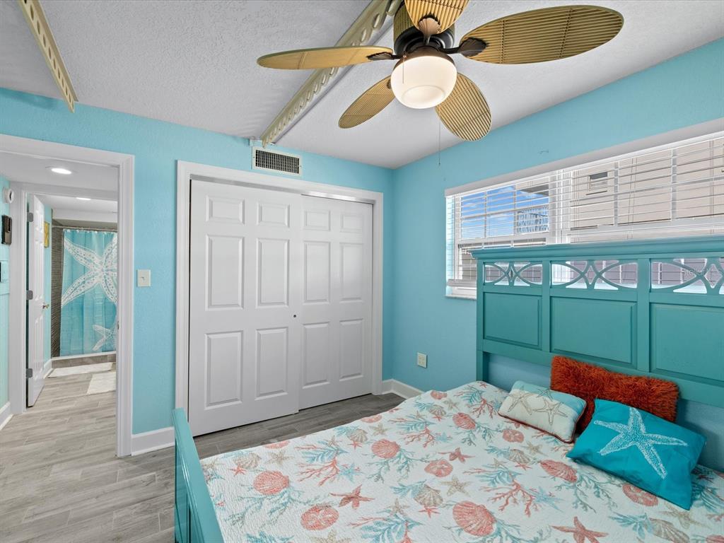 205 Dolphin Point, Unit 4 Clearwater Beach, FL 33767 - Photo 14 of 23 a bedroom with a bed and a chandelier