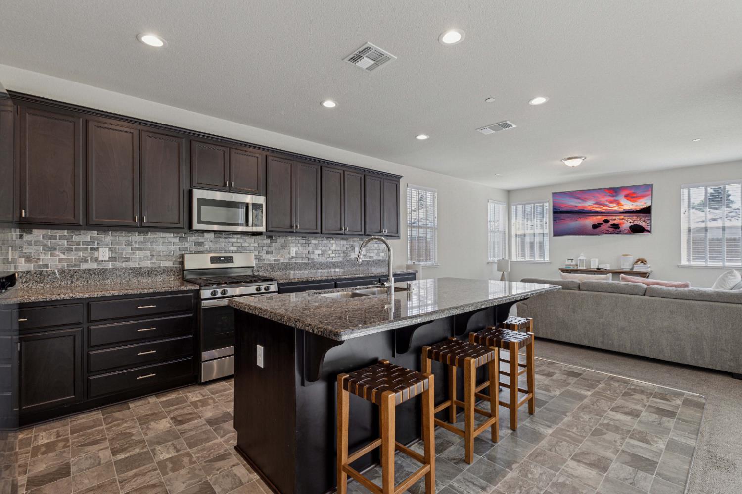 3264 Showcase Way Modesto, CA 95356 - Photo 5 of 31 a kitchen with stainless steel appliances granite countertop a stove top oven a sink a dining table and chairs with wooden floor