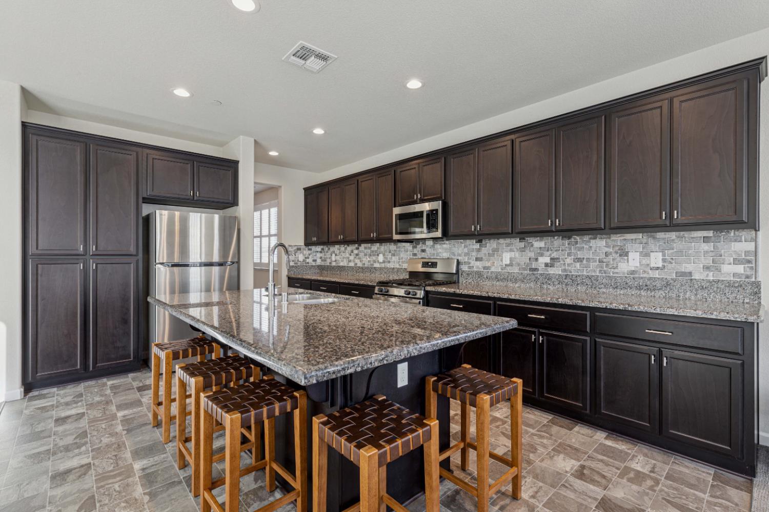 3264 Showcase Way Modesto, CA 95356 - Photo 6 of 31 a kitchen with stainless steel appliances granite countertop a stove top oven a refrigerator a sink and dishwasher with wooden cabinets