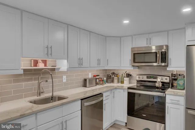 a kitchen with a sink and a stove top oven with white cabinets