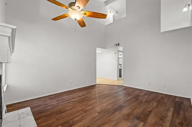 a view of an empty room with wooden floor and a bathroom