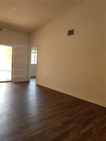 an empty room with wooden floor and windows with curtains