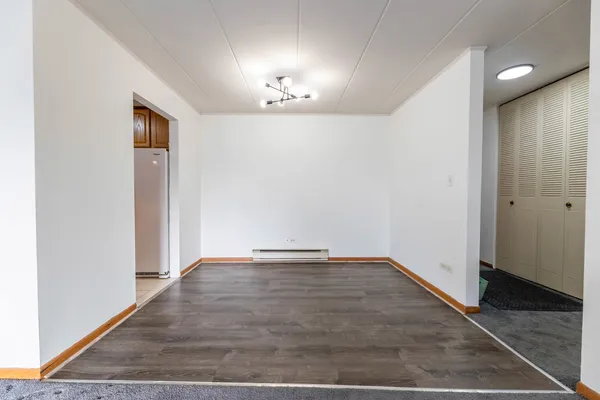 an empty room with wooden floor and hallway
