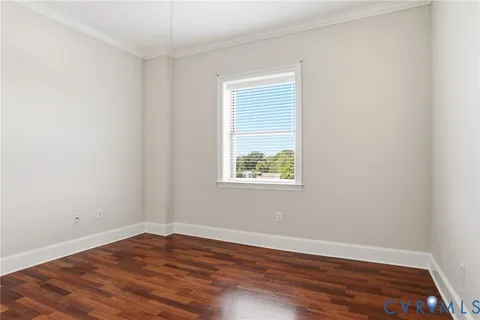 an empty room with wooden floor and window