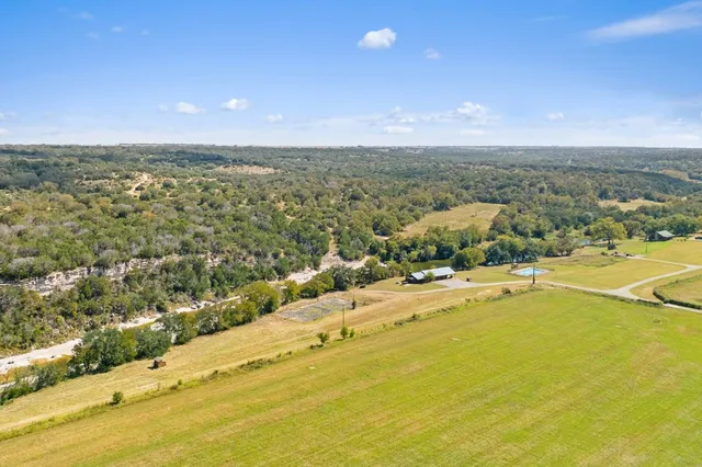 an aerial view of residential houses with outdoor space and trees all around
