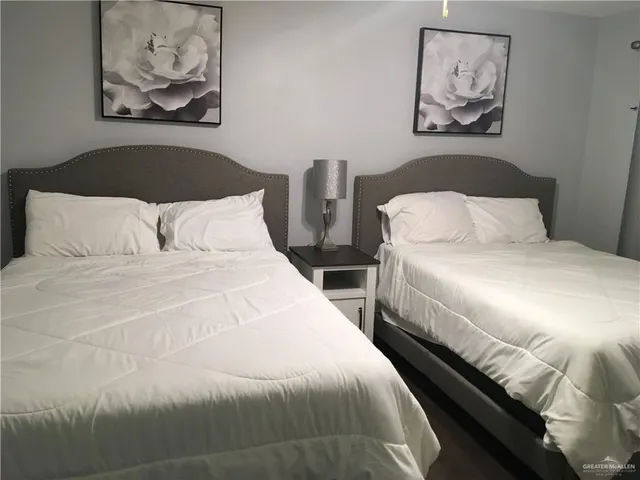 a bedroom with 2 bed and a painting on the wall