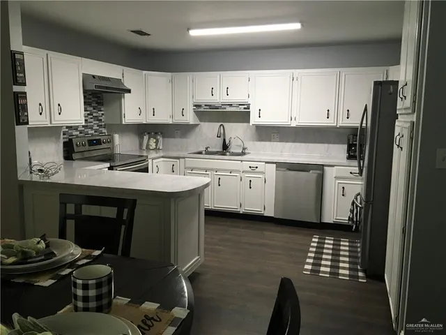 a kitchen with stainless steel appliances granite countertop a sink stove refrigerator and white cabinets
