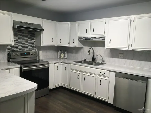 a kitchen with cabinets appliances a sink and a counter