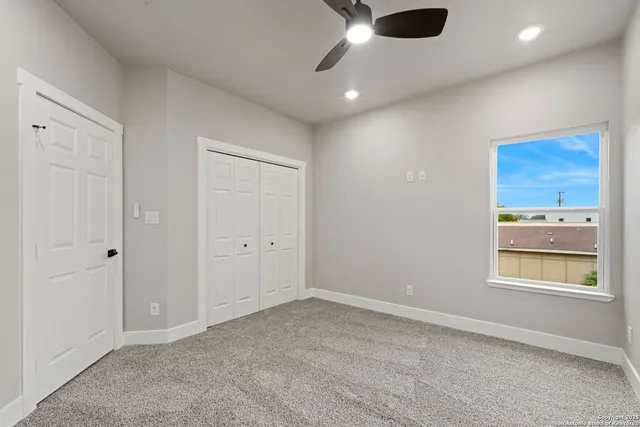 an empty room with a window and ceiling fan