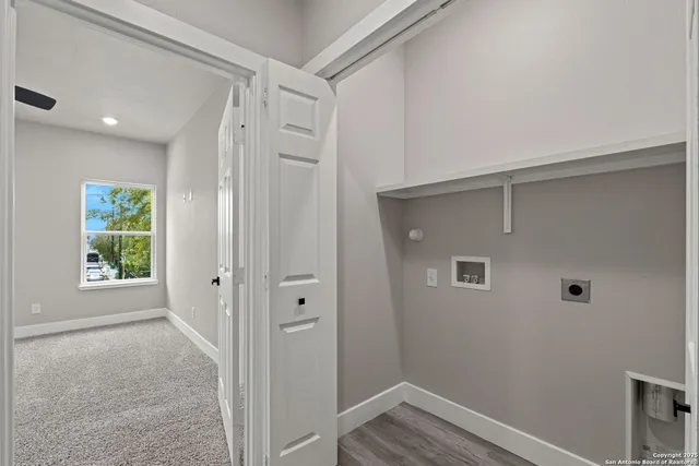 an empty room with windows and view of kitchen