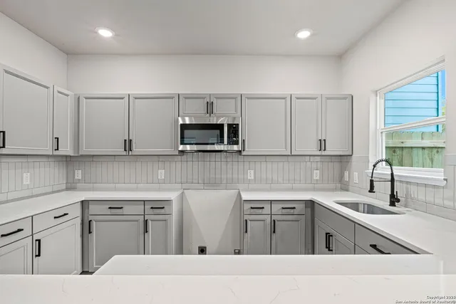 a kitchen with white cabinets appliances and a window