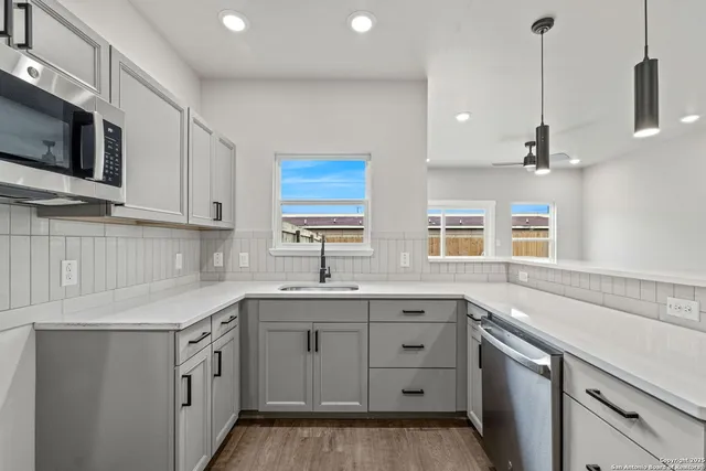 a kitchen that has a sink a window and stainless steel appliances