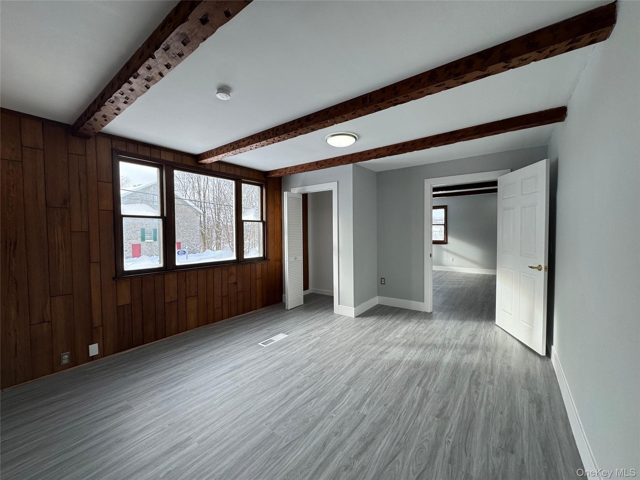 9606 Lincoln Avenue Remsen, NY 13438 - Photo 24 of 43 Unfurnished room featuring wood walls, wood finished floors, and beam ceiling