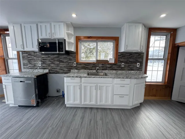 a kitchen with stainless steel appliances granite countertop a sink a stove a counter space and cabinets
