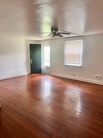 an empty room with wooden floor air conditioner and windows