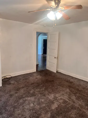 an empty room with a chandelier fan and windows