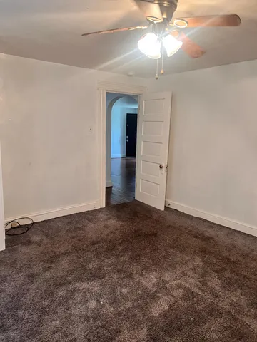 an empty room with a chandelier fan and windows