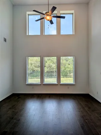 an empty room with wooden floor and windows