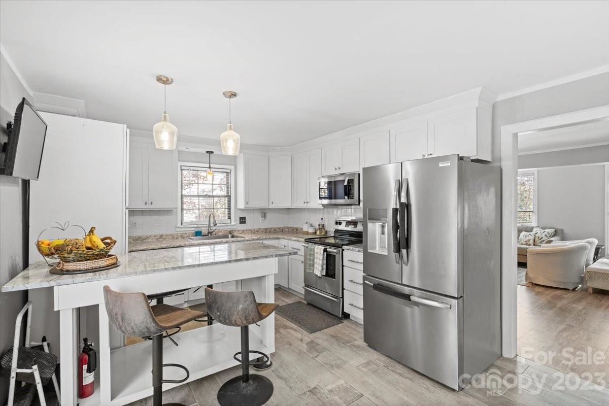 9099 Pitcairn Drive Tega Cay, SC 29708 - Photo 6 of 21 a kitchen with stainless steel appliances a refrigerator a stove a sink a dining table and chairs
