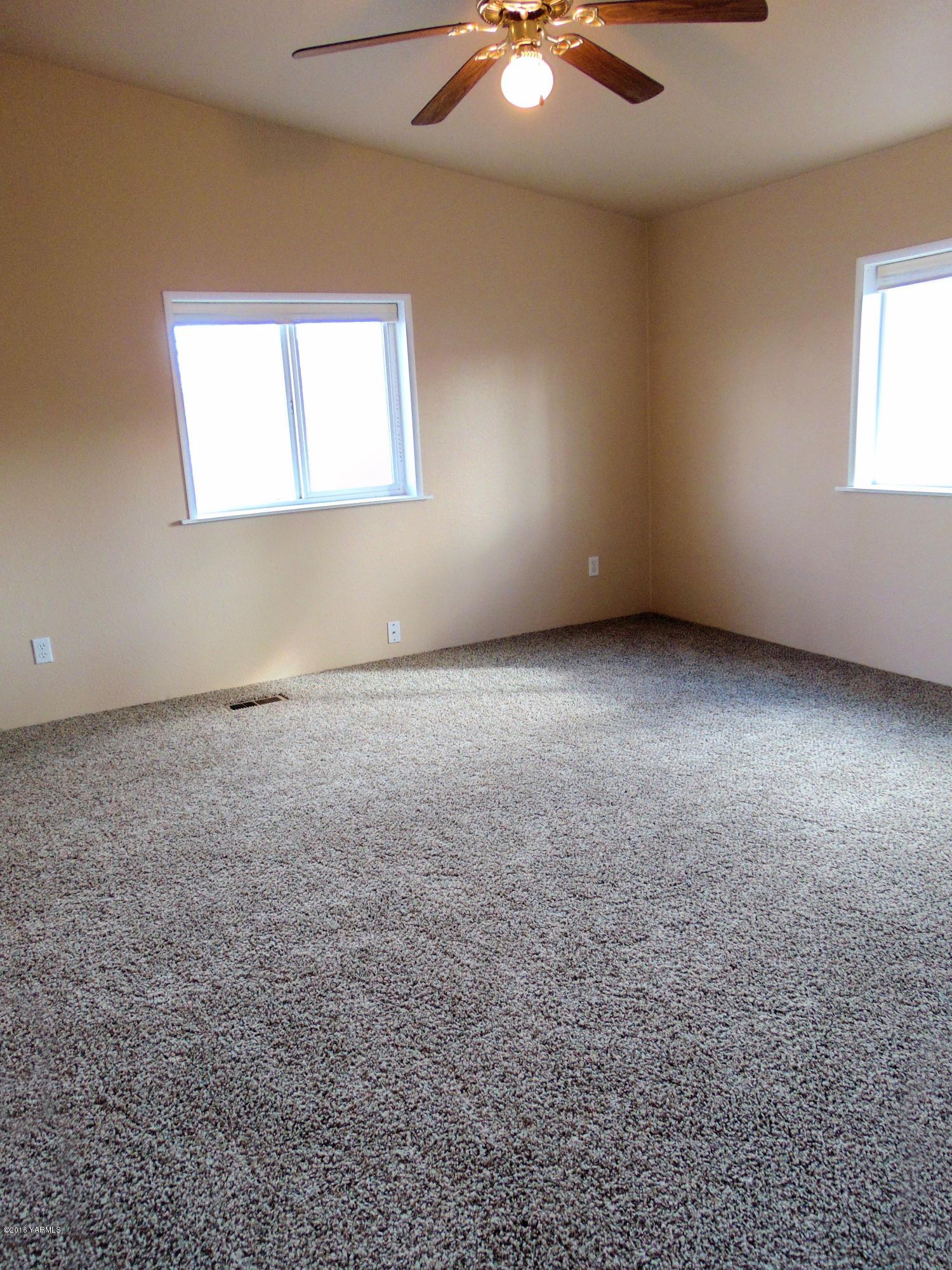 151 Cook Road Yakima, WA 98908 - Photo 9 of 13 an empty room with windows and chandelier fan