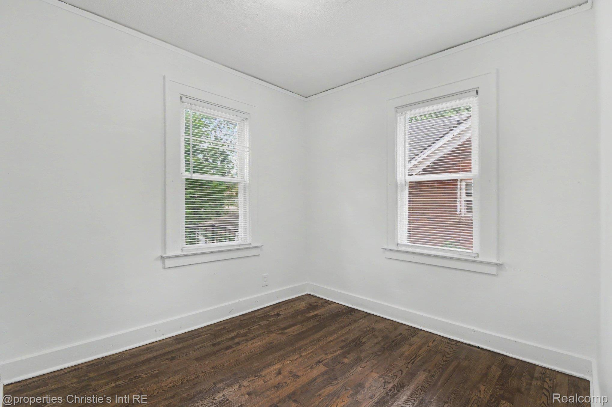 5911 Yorkshire Road Detroit, MI 48224 - Photo 10 of 14 Room featuring two double-hung windows with blinds, wood-finish flooring, white baseboards, and white wall finishes