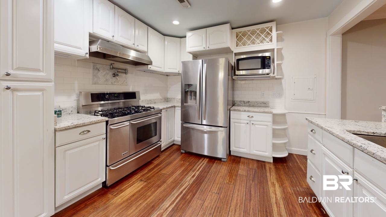 48 Hathaway Road West Mobile, AL 36608 - Photo 12 of 40 Kitchen with light stone counters, stainless steel appliances, dark hardwood / wood-style flooring, and white cabinetry