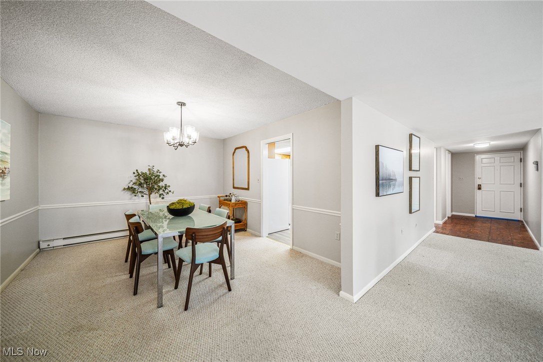 2365 Covington Road, Unit 225 Akron, OH 44313 - Photo 11 of 36 Dining area with baseboards, carpet, baseboard heating, a textured ceiling, and a notable chandelier