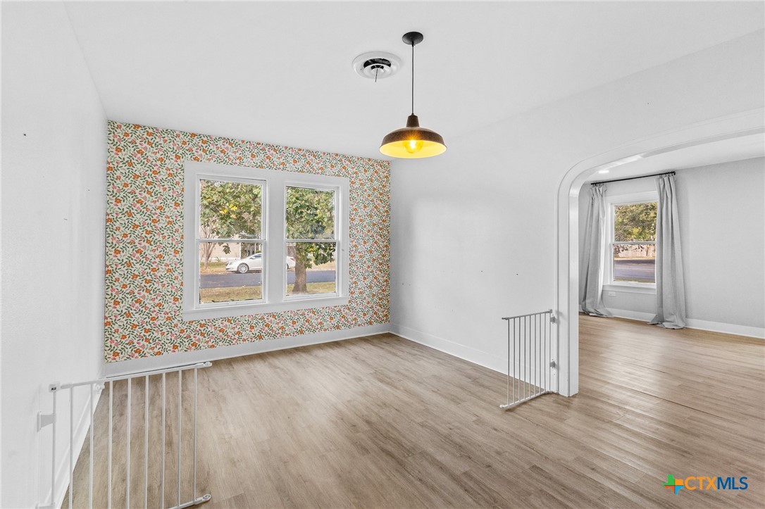 3109 North Main Street Victoria, TX 77901 - Photo 20 of 29 an empty room with wooden floor chandelier and windows