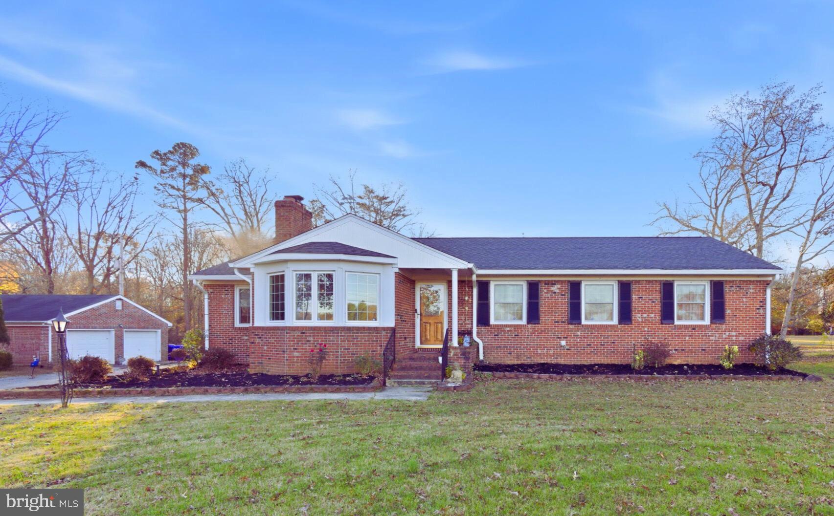 a front view of a house with a garden and trees