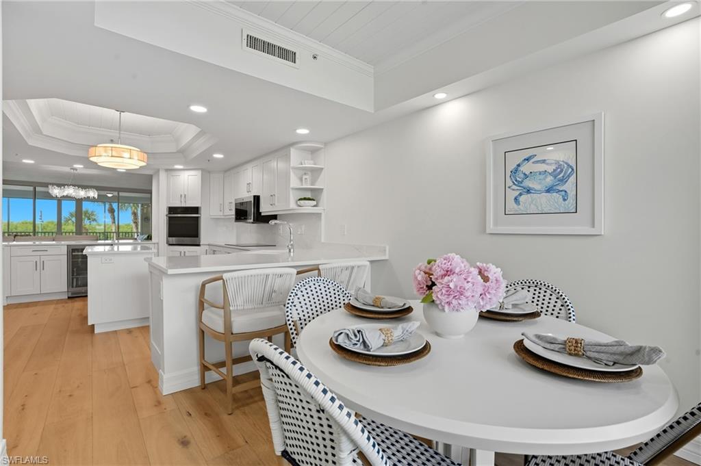 445 Dockside Drive, Unit B202 Naples, FL 34110 - Photo 21 of 50 a kitchen with stainless steel appliances kitchen island granite countertop a dining table and chairs