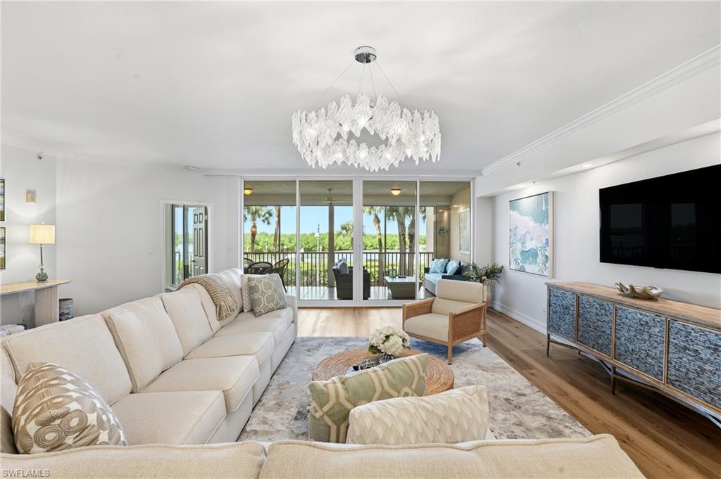 445 Dockside Drive, Unit B202 Naples, FL 34110 - Photo 6 of 50 Living Room. Featuring a sparkling chandelier and hardwood flooring throughout the common areas.