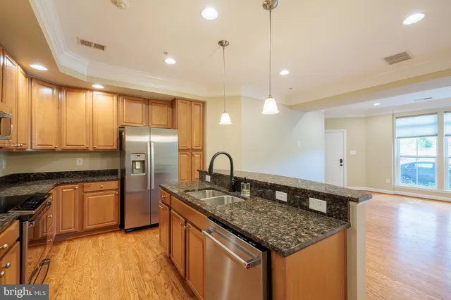 a kitchen with stainless steel appliances granite countertop a sink a refrigerator and a stove