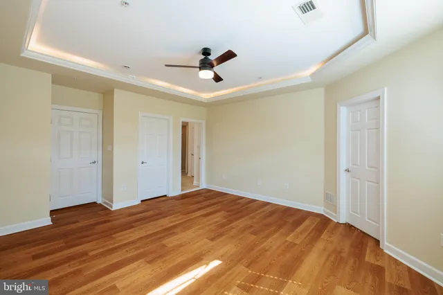 a view of empty room with wooden floor and ceiling fan