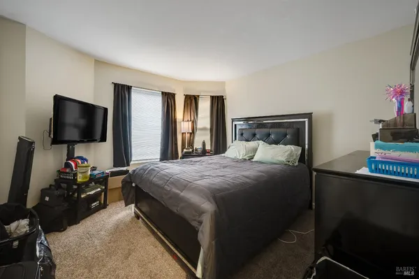 a bedroom with a bed tv and a window