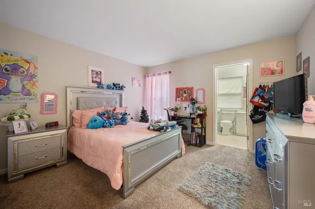 a bedroom with a bed and a flat tv screen on the dresser
