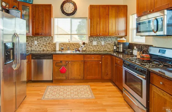 a kitchen with stainless steel appliances granite countertop a stove a sink and a microwave