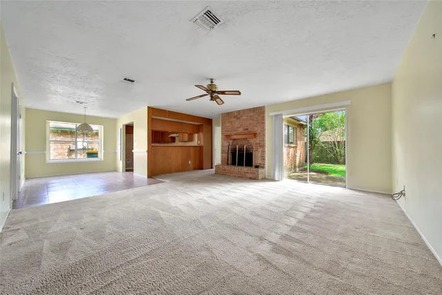 a view of an empty room with a window and a kitchen