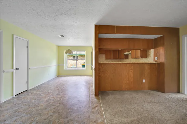 an empty room with kitchen and windows
