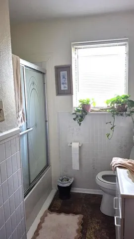 a bathroom with a toilet a window and tub
