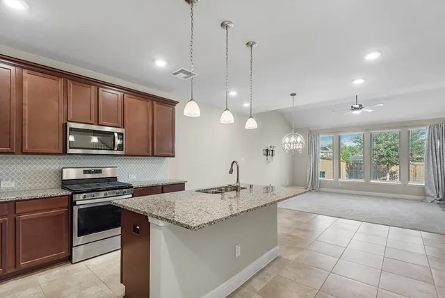 a large kitchen with kitchen island granite countertop a stove a sink and a granite counter tops