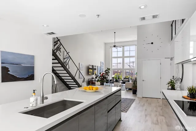 a kitchen with kitchen island granite countertop a sink a stove and white cabinets