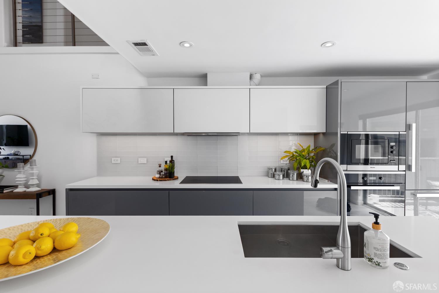 229 8th Street, Unit 3 San Francisco, CA 94103 - Photo 25 of 61 a kitchen with kitchen island granite countertop a sink a stove and white cabinets