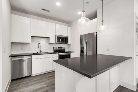 a kitchen with stainless steel appliances granite countertop a sink a stove a refrigerator a center island with wooden floor