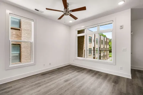 a view of an empty room with a window and wooden floor