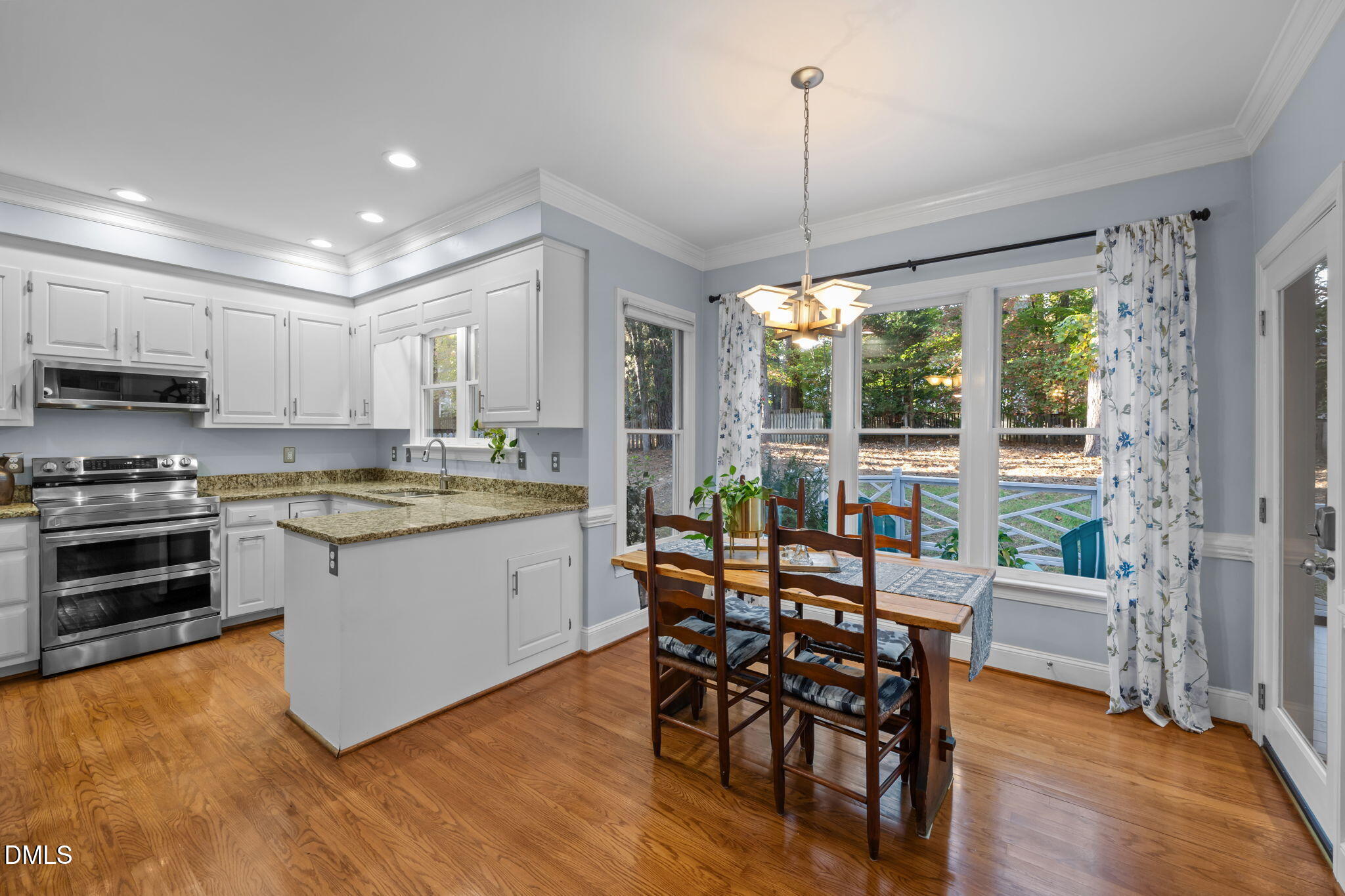 4304 Omni Place Raleigh, NC 27613 - Photo 15 of 58 a kitchen with stainless steel appliances granite countertop a stove top oven a sink dishwasher a dining table and chairs with wooden floor